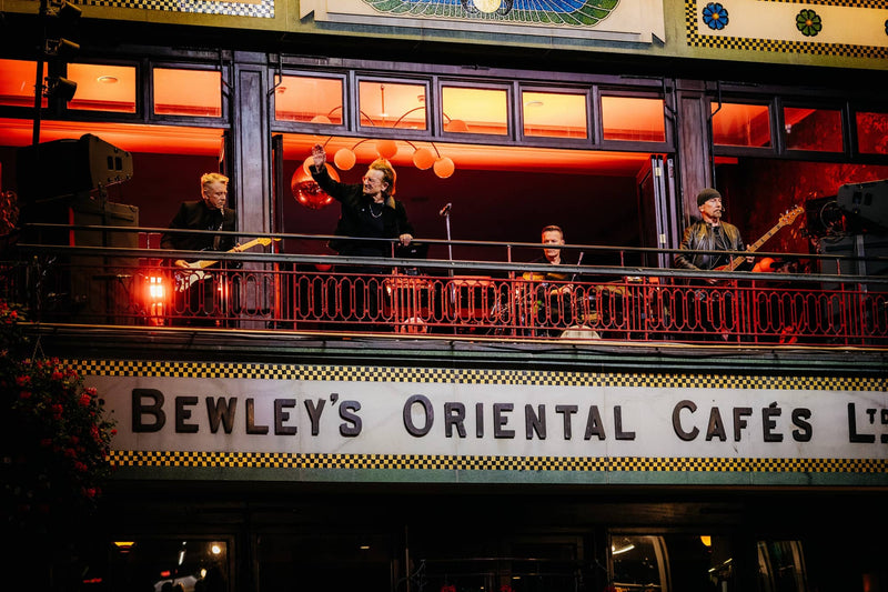 The illuminated sign for bewley’s oriental cafés, featuring bold black lettering on a white background with decorative yellow and black checkered borders.