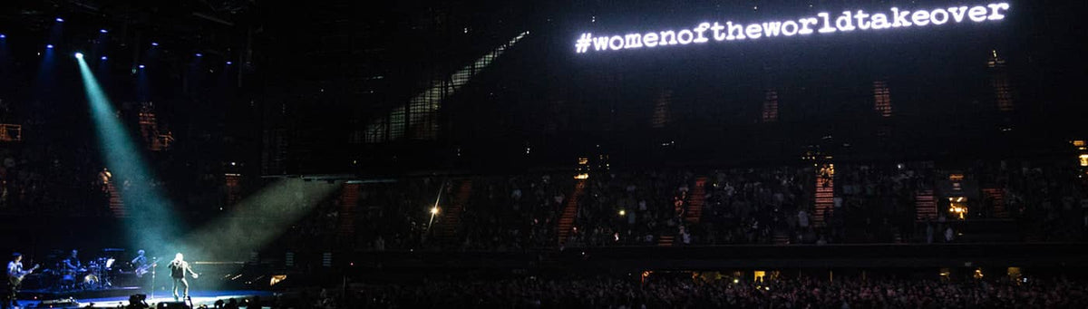 A glowing white led screen displaying the hashtag #womenoftheworldtakeover.